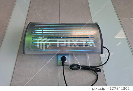 An ultraviolet lamp designed to kill insects is installed at the supermarket entrance, attracting pests and enhancing cleanliness. This tool is vital for maintaining a hygienic shopping environment. 127841805