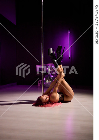 Enjoy a captivating pole dance performance under vibrant lights, blending athleticism and artistry Enjoy a captivating pole dance performance under vibrant lights, blending athleticism and artistry 127841845