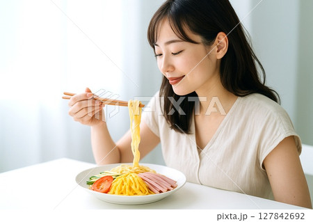 冷やし中華を食べる女性　夏の涼感と笑顔の食卓シーン 127842692
