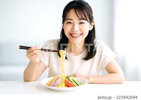 冷やし中華を食べる女性　夏の涼感と笑顔の食卓シーン 127842694