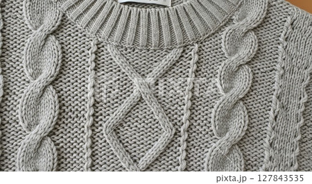 Close Up Detailed Texture of Soft Gray Cable Knit Wool Sweater Showing Intricate Knitting Pattern 127843535