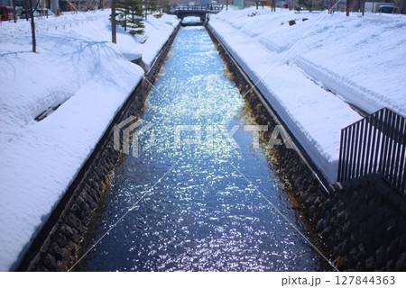 雪に包まれた川辺と水面が輝く冬の静かな風景 雪に包まれた川辺と水面が輝く冬の静かな風景 127844363