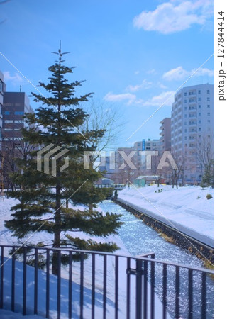 雪景色の川と都市の風景にそびえる針葉樹のある冬の日 127844414