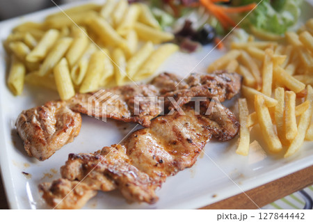 Grilled Chicken with Pasta, Fries, and Fresh Salad on a White Plate 127844442