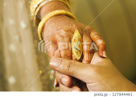 Close-Up of Elegant Hand Jewelry and Holding Hands in Warm Lighting 127844461