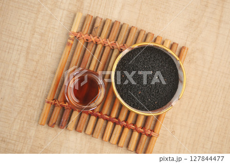 Black Seeds and Their Oil Beautifully Arranged in a Rustic Wooden Bowl for Culinary Uses 127844477