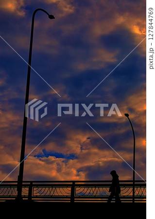 夕焼けに染まる橋を渡る歩行者 夕焼けに染まる橋を渡る歩行者 127844769