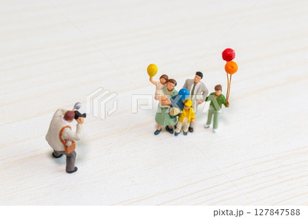 Miniature Family Posing for Photographer with Balloons 127847588