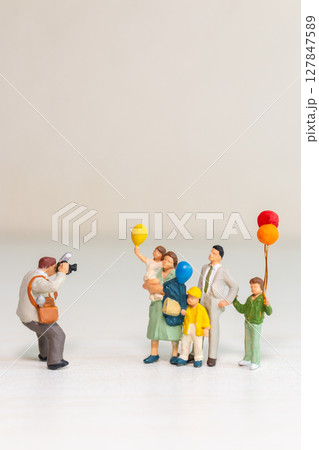 Miniature Family Posing for Photographer with Balloons 127847589