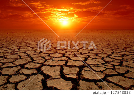Dramatic Sunset over Cracked Earth Landscape with Vintage Orange and Red Sky Colors 127848838