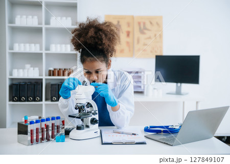 Young scientists conducting research investigations in a medical laboratory, a researcher in the foreground is using a microscope in laboratory for medicine. 127849107