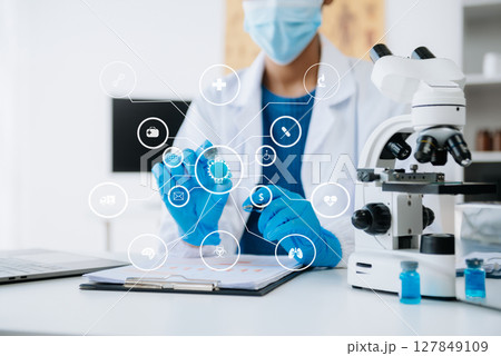 Young scientists conducting research investigations in a medical laboratory, a researcher in the foreground is using a microscope in laboratory for medicine. Young scientists conducting research investigations in a medical laboratory, a researcher in the foreground is using a microscope in laboratory for medicine. 127849109