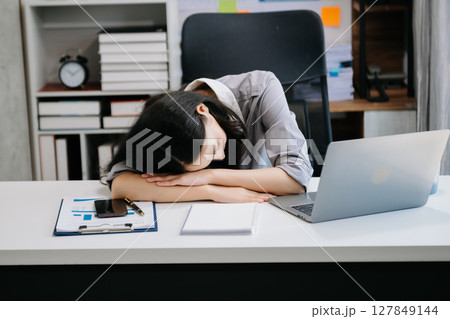 Asian woman feeling migraine head strain.Overworked businesswoman financier while working on laptop and tablet Asian woman feeling migraine head strain.Overworked businesswoman financier while working on laptop and tablet 127849144