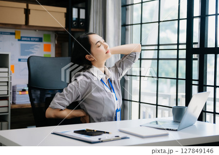 Asian woman feeling migraine head strain.Overworked businesswoman financier while working on laptop and tablet Asian woman feeling migraine head strain.Overworked businesswoman financier while working on laptop and tablet 127849146