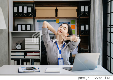Asian woman feeling migraine head strain.Overworked businesswoman financier while working on laptop and tablet 127849148