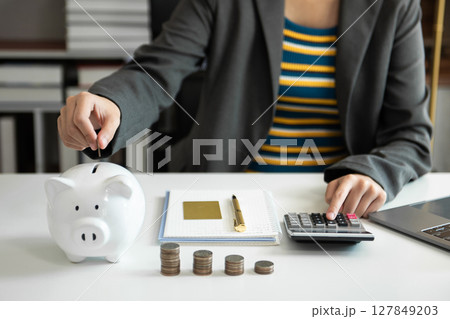 Business woman hand putting money coin into piggy bank with step of growing stack coins for saving money with virtual icon 127849203