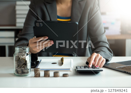 saving money with hand putting coins in jug glass and calculator to calculate budget concept finance and accounting 127849241