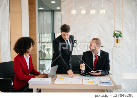 Group of young business people discussing business plan at modern startup in creative business discussing work modern office building Group of young business people discussing business plan at modern startup in creative business discussing work modern office building 127849296