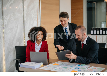 Group of young business people discussing business plan at modern startup in creative business discussing work modern office building Group of young business people discussing business plan at modern startup in creative business discussing work modern office building 127849297