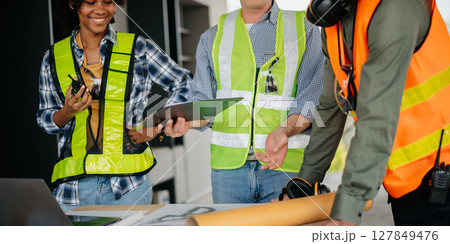 Engineers are discussing data working and laptop or tablet with architectural project at new construction site on big project. Engineers are discussing data working and laptop or tablet with architectural project at new construction site on big project. 127849476