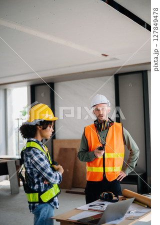 Architect caucasian man working with colleagues mixed race in the construction site. Architecture engineering on big project. Building in construction interior. 127849478