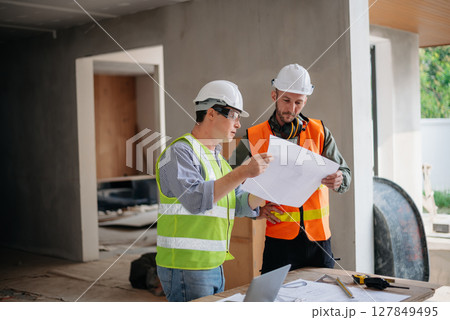 Engineers are discussing data working and laptop or tablet with architectural project at new construction site on big project. 127849495