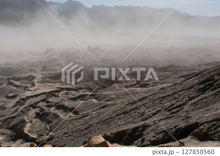 The rough surface, with layers of rocks piled on top of each other far into the distance. Covered by a sandstorm around the mountain Bromo, Indonesia 127850560