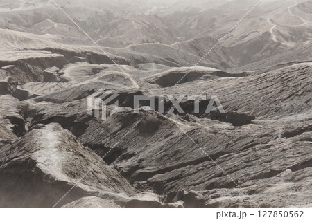 The rough surface, with layers of rocks piled on top of each other far into the distance. Covered by a sandstorm around the mountain Bromo, Indonesia The rough surface, with layers of rocks piled on top of each other far into the distance. Covered by a sandstorm around the mountain Bromo, Indonesia 127850562