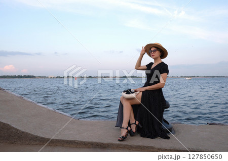 Woman in polka-dot dress poses by the waterfront promenade. Woman in polka-dot dress poses by the waterfront promenade. 127850650