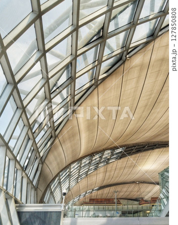 the intricate architecture of a modern airport terminal, focusing on the sweeping curved roof and structural elements 127850808