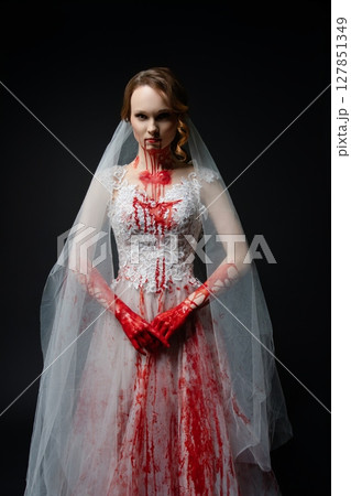 Woman in bridal lingerie holds katana with bloodstains in dark setting Woman in bridal lingerie holds katana with bloodstains in dark setting 127851349