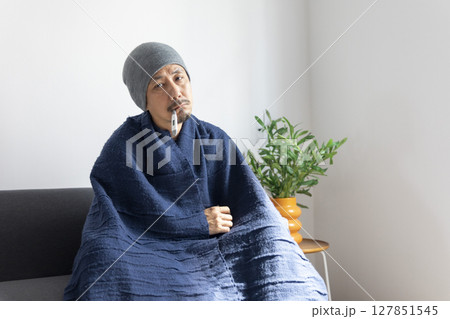 Asian man sick or ill and coughing by covering their mouth with napkin paper while sitting on the sofa at home. Asian man sick or ill and coughing by covering their mouth with napkin paper while sitting on the sofa at home. 127851545