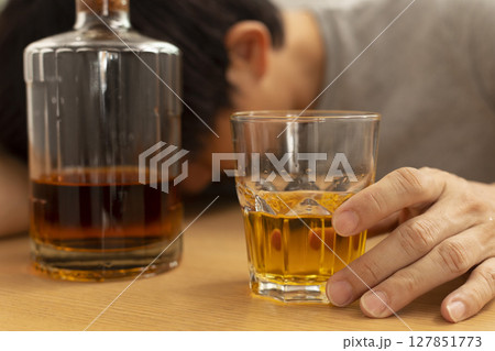 Alcohol addicted man sleeping at the table. Sad depressed male adult having troubles with alcohol. 127851773