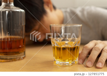 Alcohol addicted man sleeping at the table. Sad depressed male adult having troubles with alcohol. 127851775