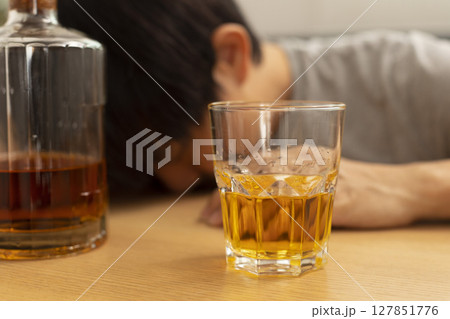 Alcohol addicted man sleeping at the table. Sad depressed male adult having troubles with alcohol. 127851776