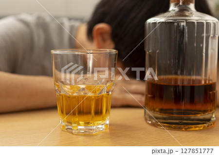 Alcohol addicted man sleeping at the table. Sad depressed male adult having troubles with alcohol. 127851777