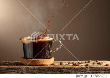 Black coffee in glass cup on a brown background. 127853227