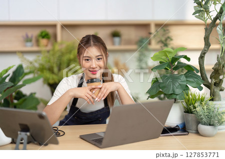 Remote Work and Wellness. Young woman enjoying coffee while working on a laptop. Remote Work and Wellness. Young woman enjoying coffee while working on a laptop. 127853771