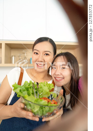 Healthy Cooking and Bonding. Two women preparing fresh salad together in a modern kitchen. 127853772