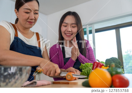 Cooking Together. Two women enjoying a fun cooking session with fresh ingredients. 127853788