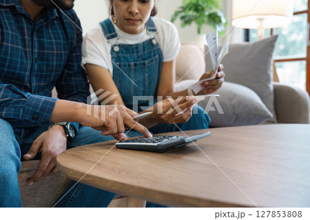 Indian Couple Managing Finances at Home, Paying Bills, and Planning Budget Together in a Modern Living Room 127853808