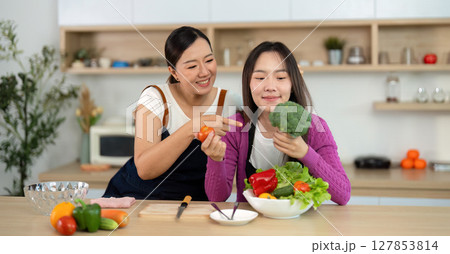 Healthy Cooking Experience. Two women enjoying vibrant vegetables in a bright kitchen. Healthy Cooking Experience. Two women enjoying vibrant vegetables in a bright kitchen. 127853814