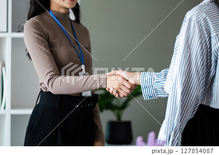 Two businesswomen shake hand after meeting and agreement on partnership and strategy about financial 127854087