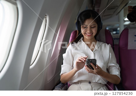 Asian business woman on aeroplane using smartphone 127854230