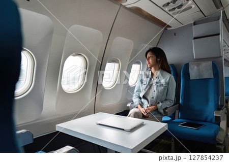 Asian people female person onboard, airplane window, looking at window while on the plane Asian people female person onboard, airplane window, looking at window while on the plane 127854237