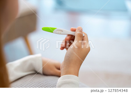 young woman hold in hands positive or negative pregnancy test thinking pondering, millennial female expecting baby undergo fertility infertility treatment 127854348