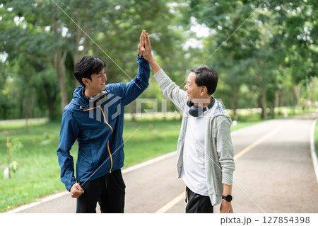 Father and Son Celebrating Together. A high-five moment during their workout. Father and Son Celebrating Together. A high-five moment during their workout. 127854398