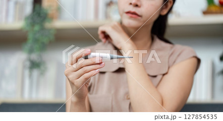 Health Monitoring. Woman checking her temperature with a digital thermometer at home. Health Monitoring. Woman checking her temperature with a digital thermometer at home. 127854535