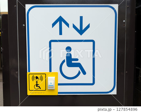 Sign indicating an accessibility elevator for people with disabilities, featuring up and down arrows, wheelchair symbol and yellow call button with braille and alert icon for assistance 127854896