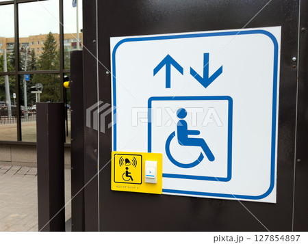 Close up view of accessibility lift call button and sign at a public building entrance, highlighting inclusive infrastructure and wheelchair accessibility in urban environments Close up view of accessibility lift call button and sign at a public building entrance, highlighting inclusive infrastructure and wheelchair accessibility in urban environments 127854897